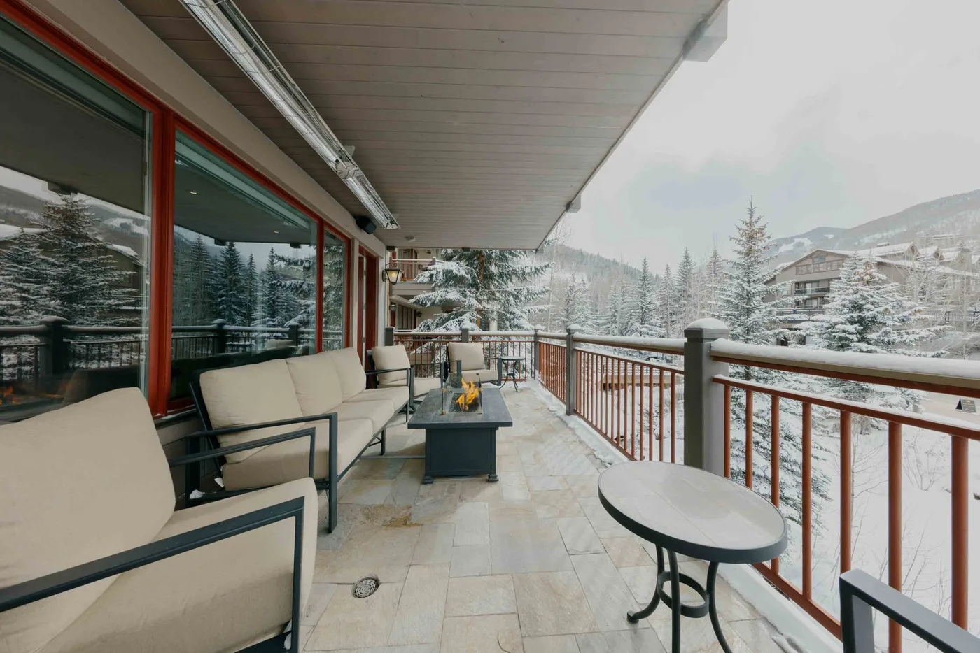 A covered outdoor seating area overlooks a snowy mountain landscape.