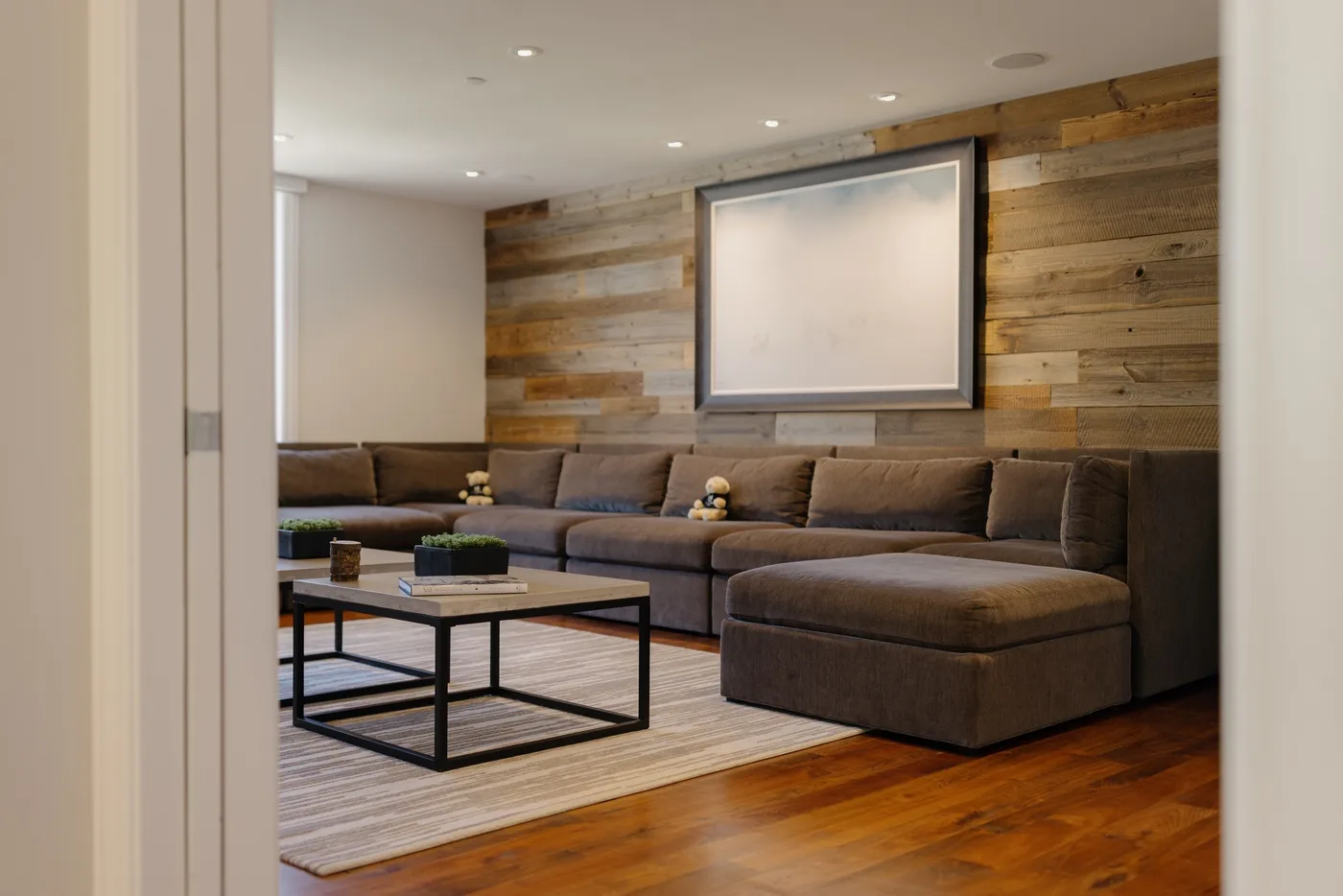 A lounge with sectional seating, a coffee table, and a wood-plank wall.
