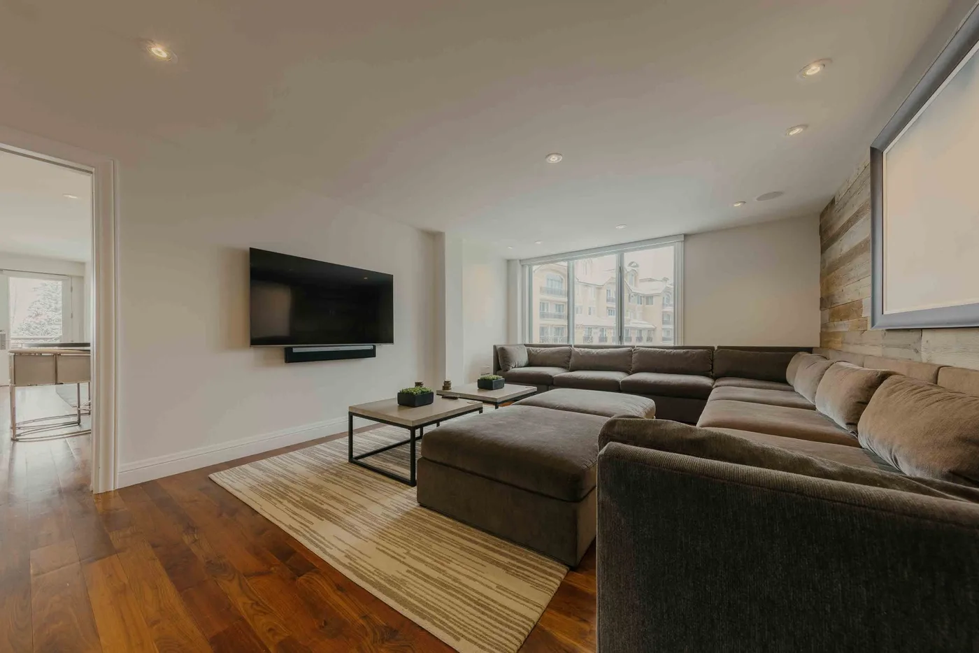 A living room with sectional seating, a wall-mounted television, and a coffee table.