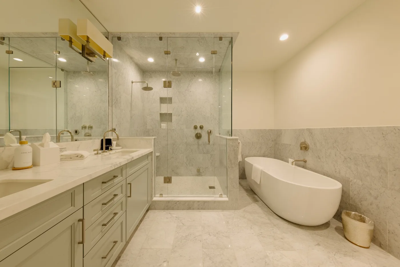 A bright bathroom with a long vanity, glass shower, and freestanding bathtub.