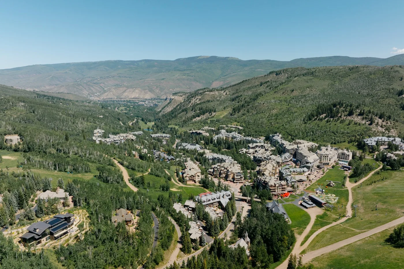 A mountain valley with wooded slopes, scattered buildings, and winding roads.