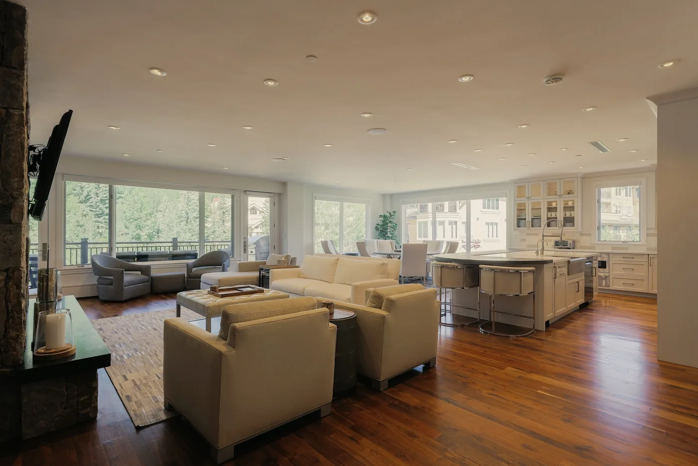 An open-plan living room and kitchen with seating, an island, and large windows.