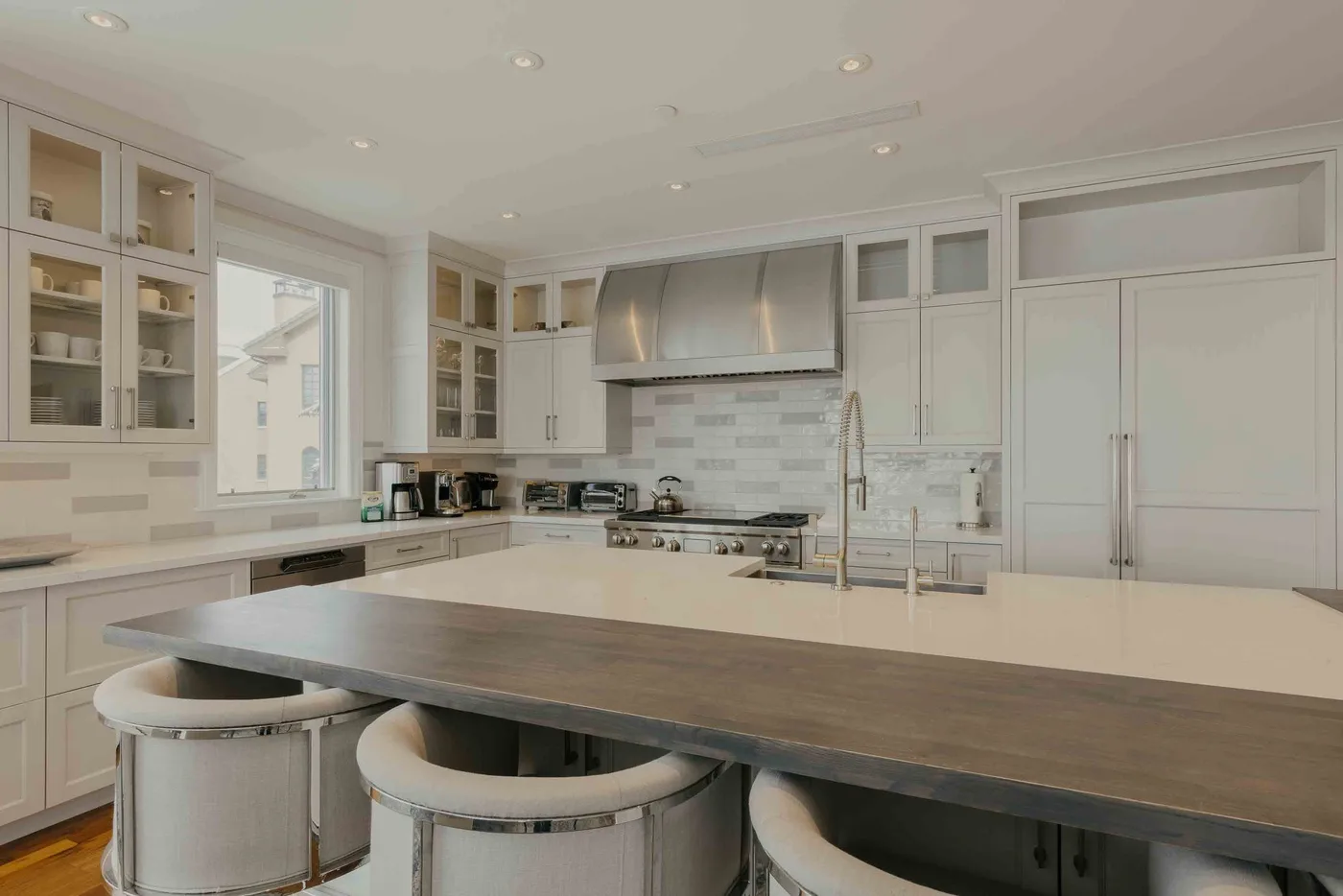 A bright kitchen with white cabinetry, a large island, and bar seating.