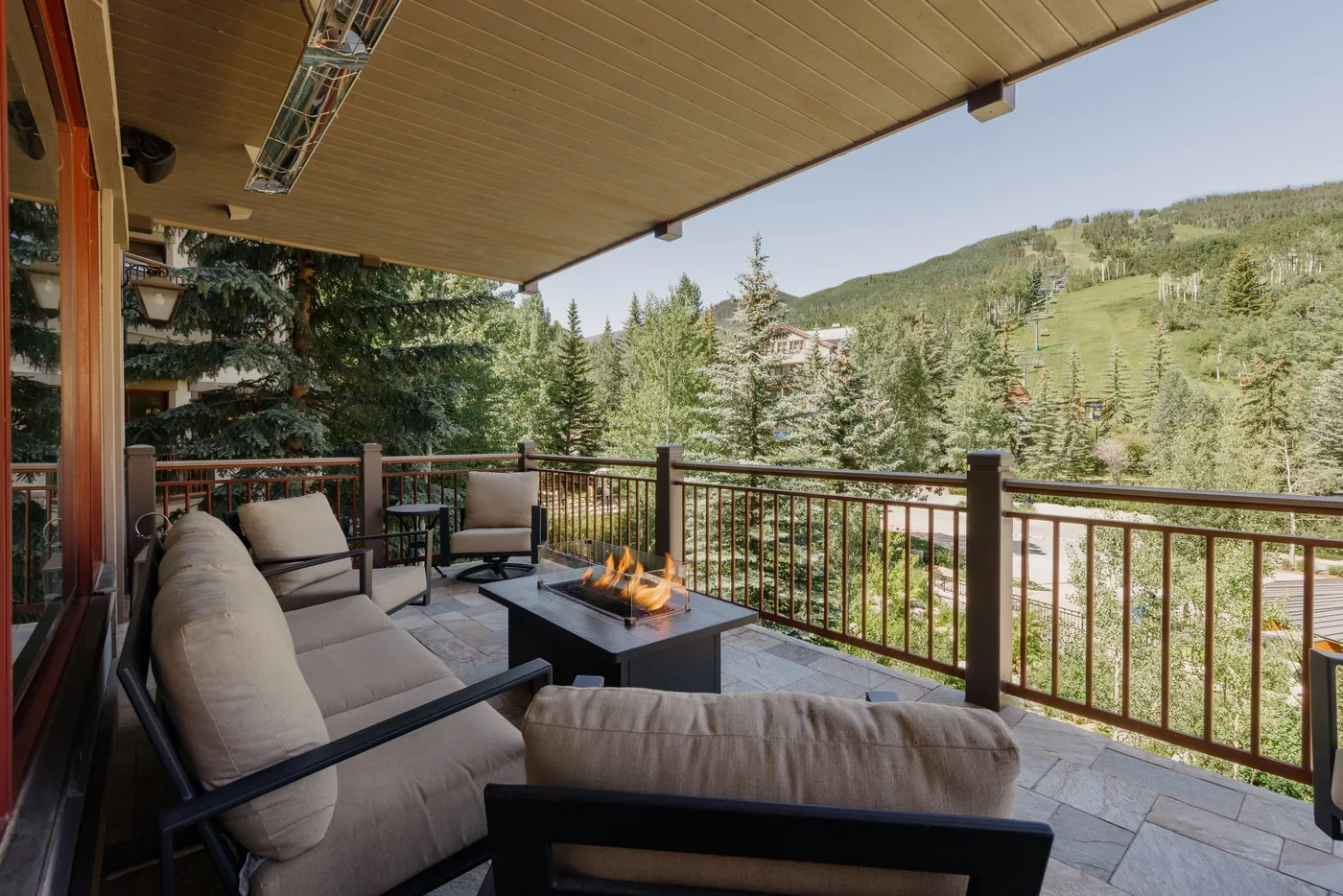 A covered outdoor seating area overlooks trees and a green hillside.