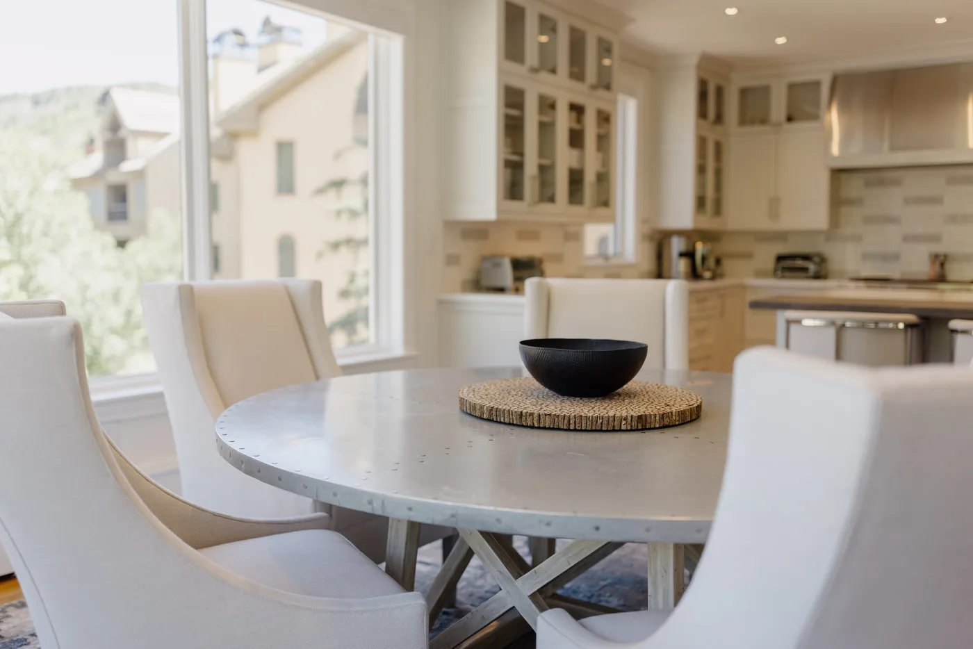 A bright kitchen and dining area with a round table and pale seating.