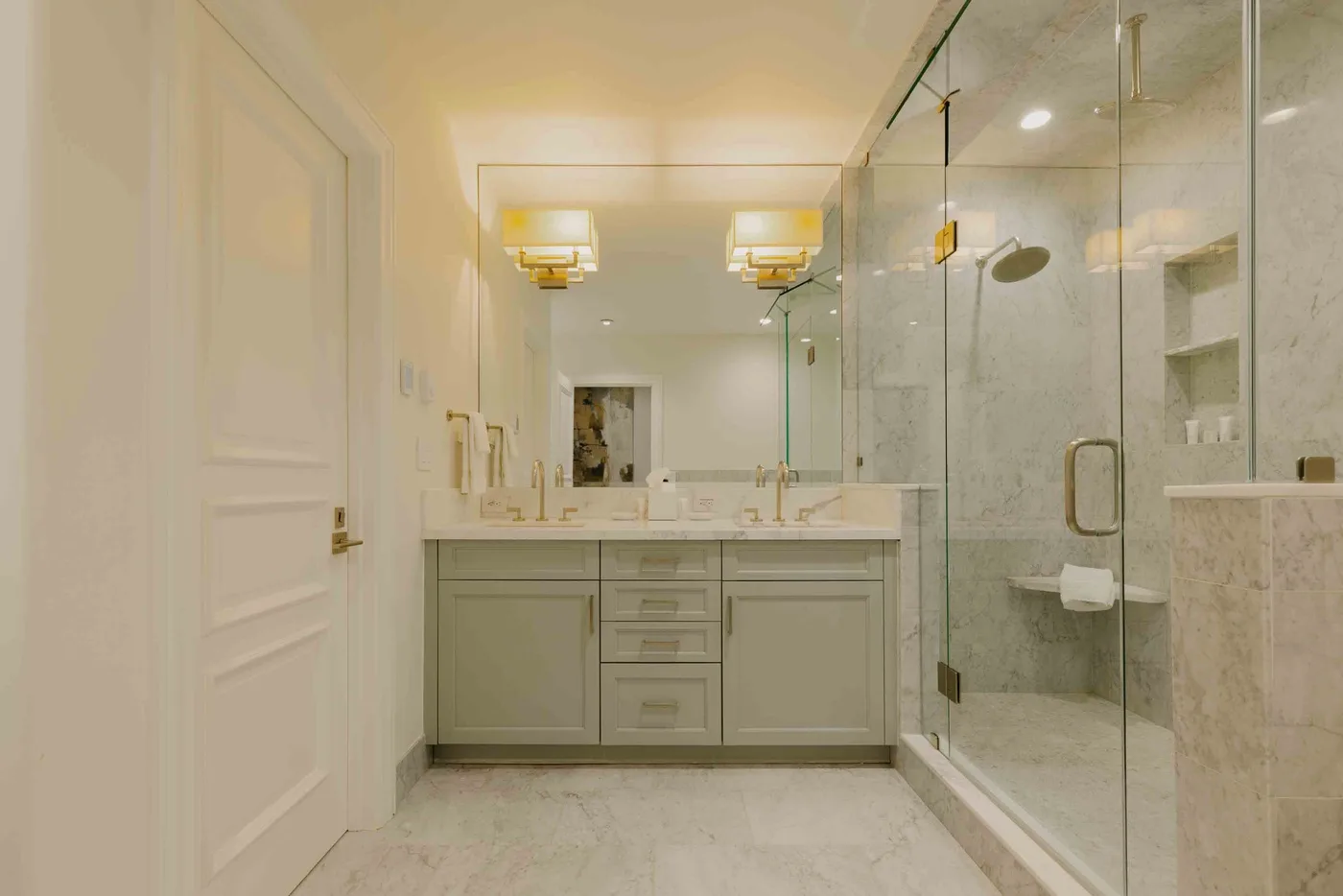 A bright bathroom with a long vanity and a glass-enclosed shower.