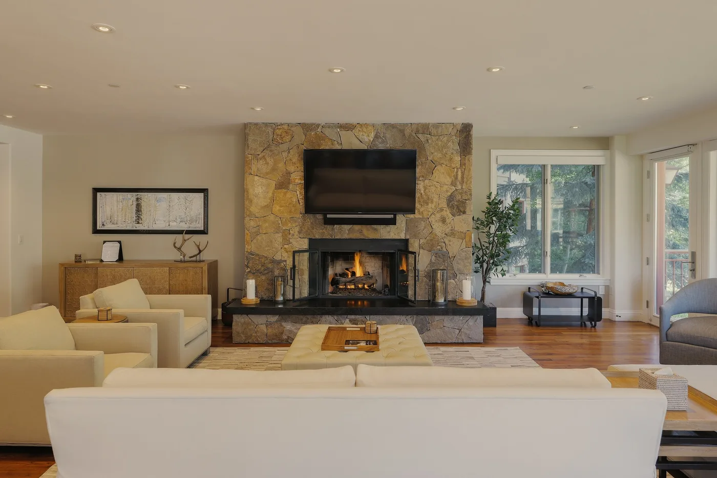 A living room with a stone fireplace and seating arranged around a coffee table.