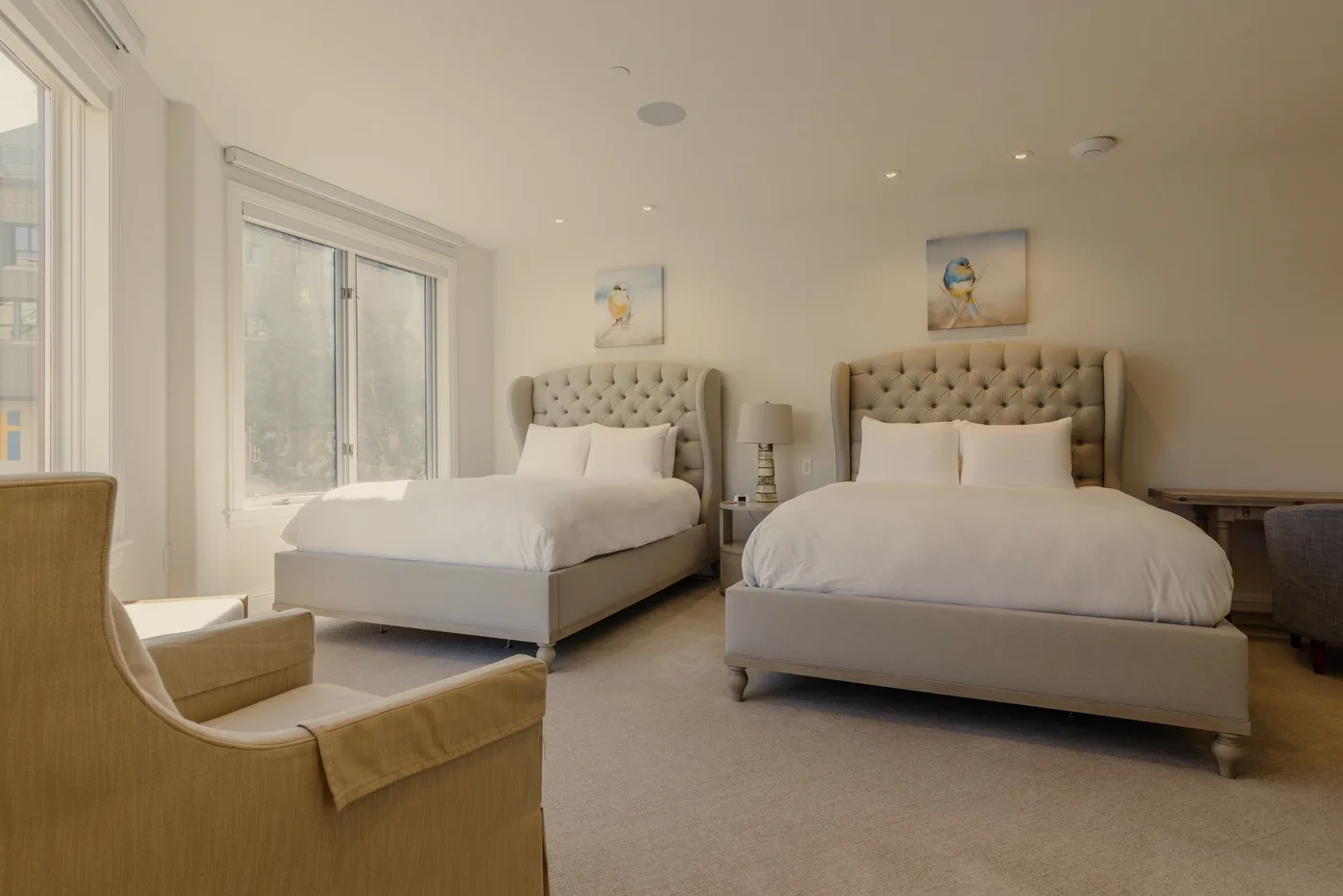 A bright bedroom with two beds and large windows.