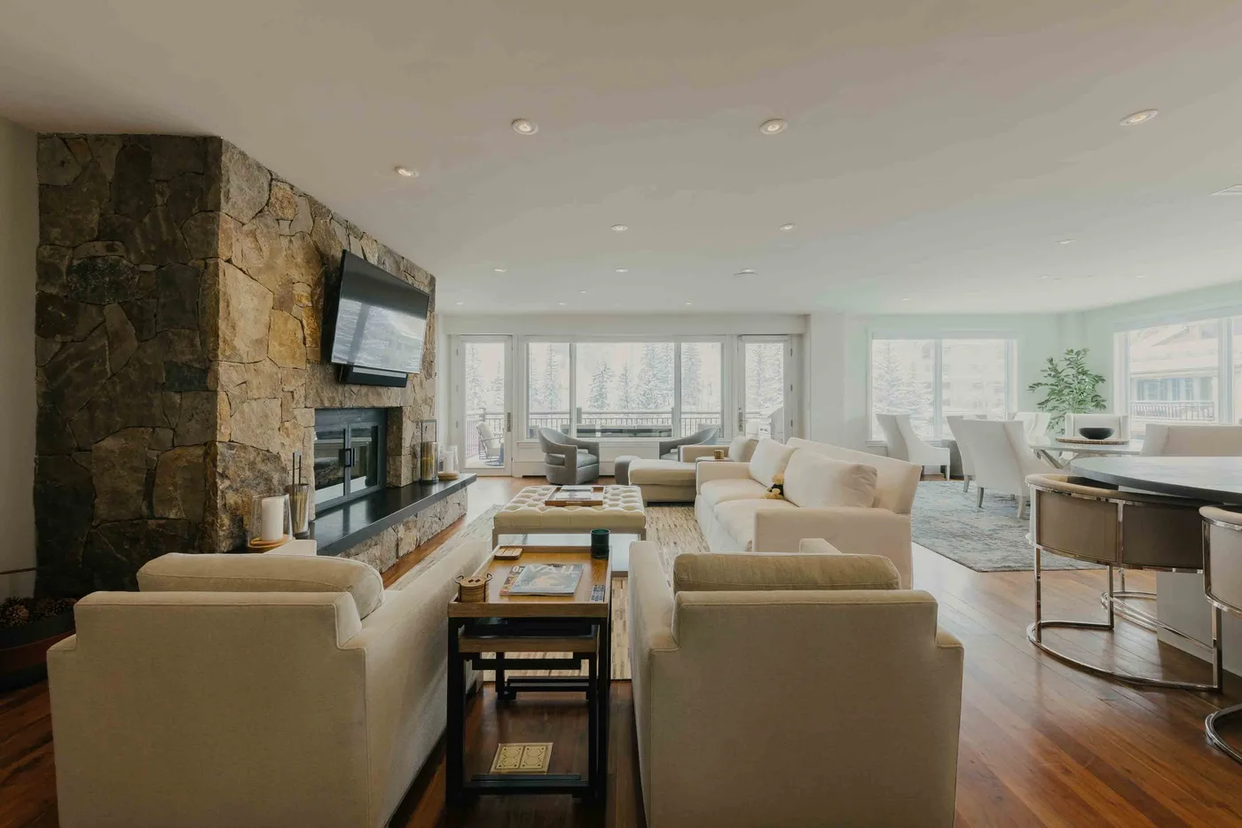 A bright living room with seating around a low table and a stone fireplace.