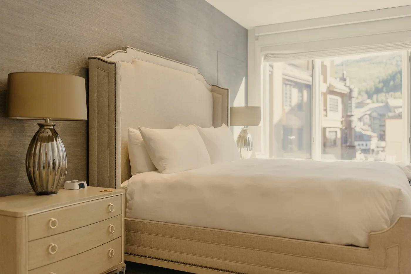 A bright bedroom with a neatly made bed and a large window.