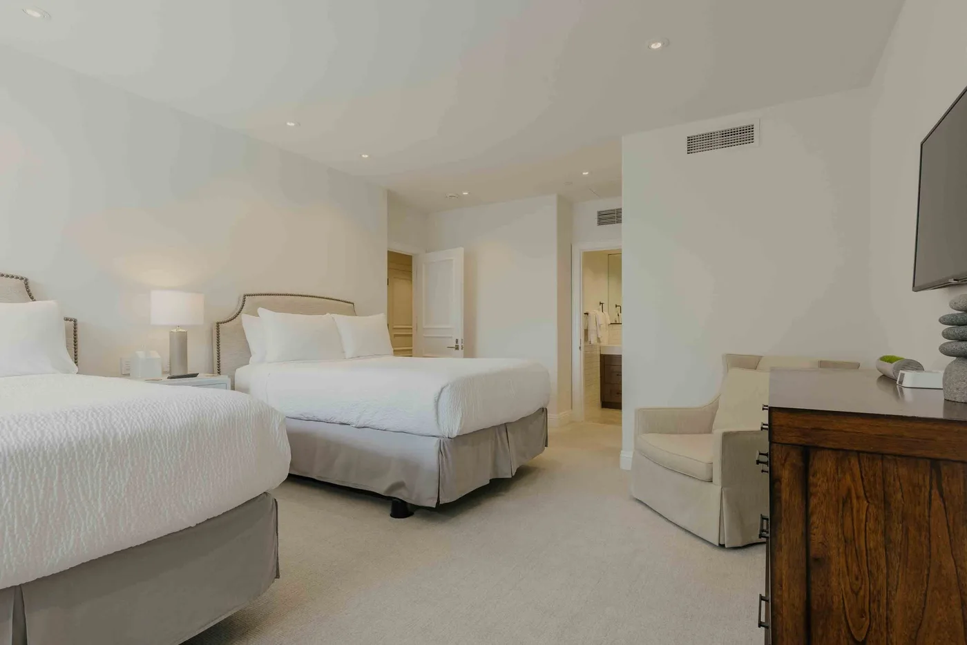 A bright bedroom with two beds and a small seating area.