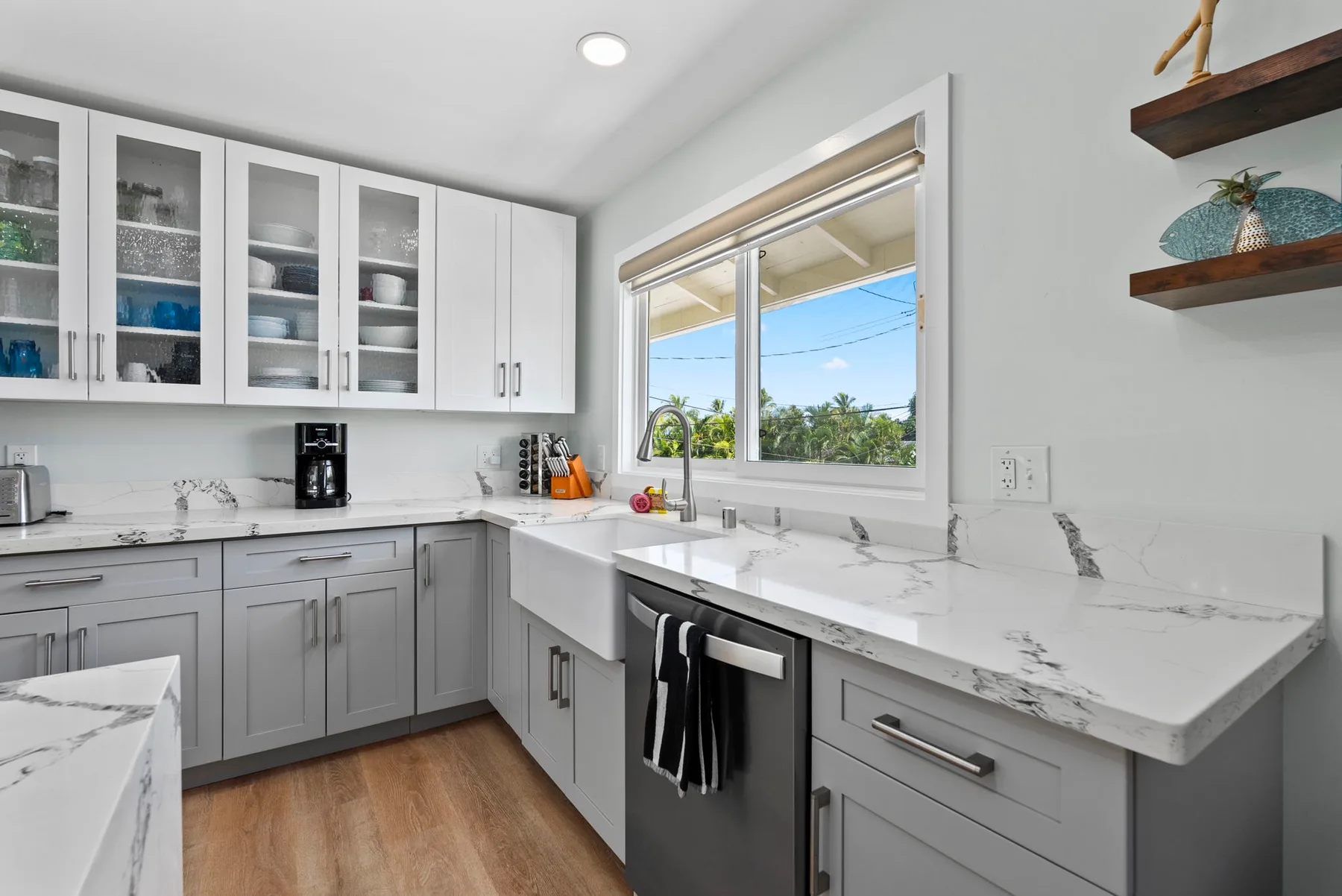 Una cocina luminosa con gabinetes blancos, una encimera jaspeada y una ventana.