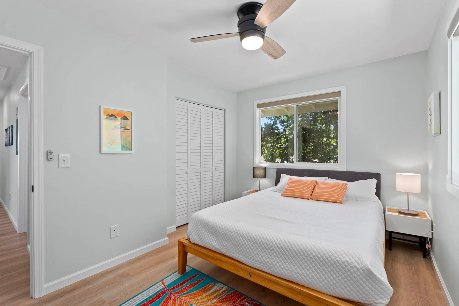 Un dormitorio luminoso con una cama bajo una ventana y un ventilador de techo.