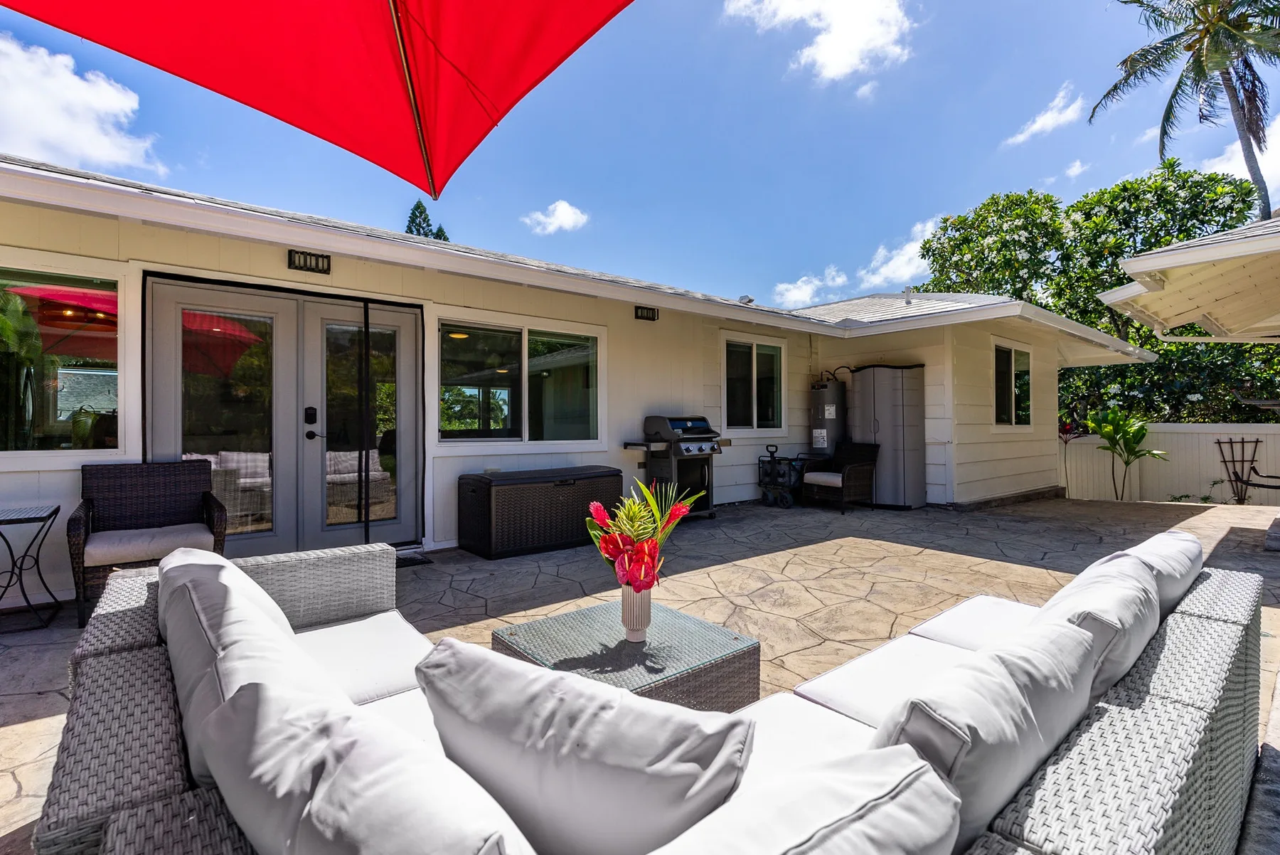Un patio exterior con asientos acolchados, una mesa baja y vista a la casa.