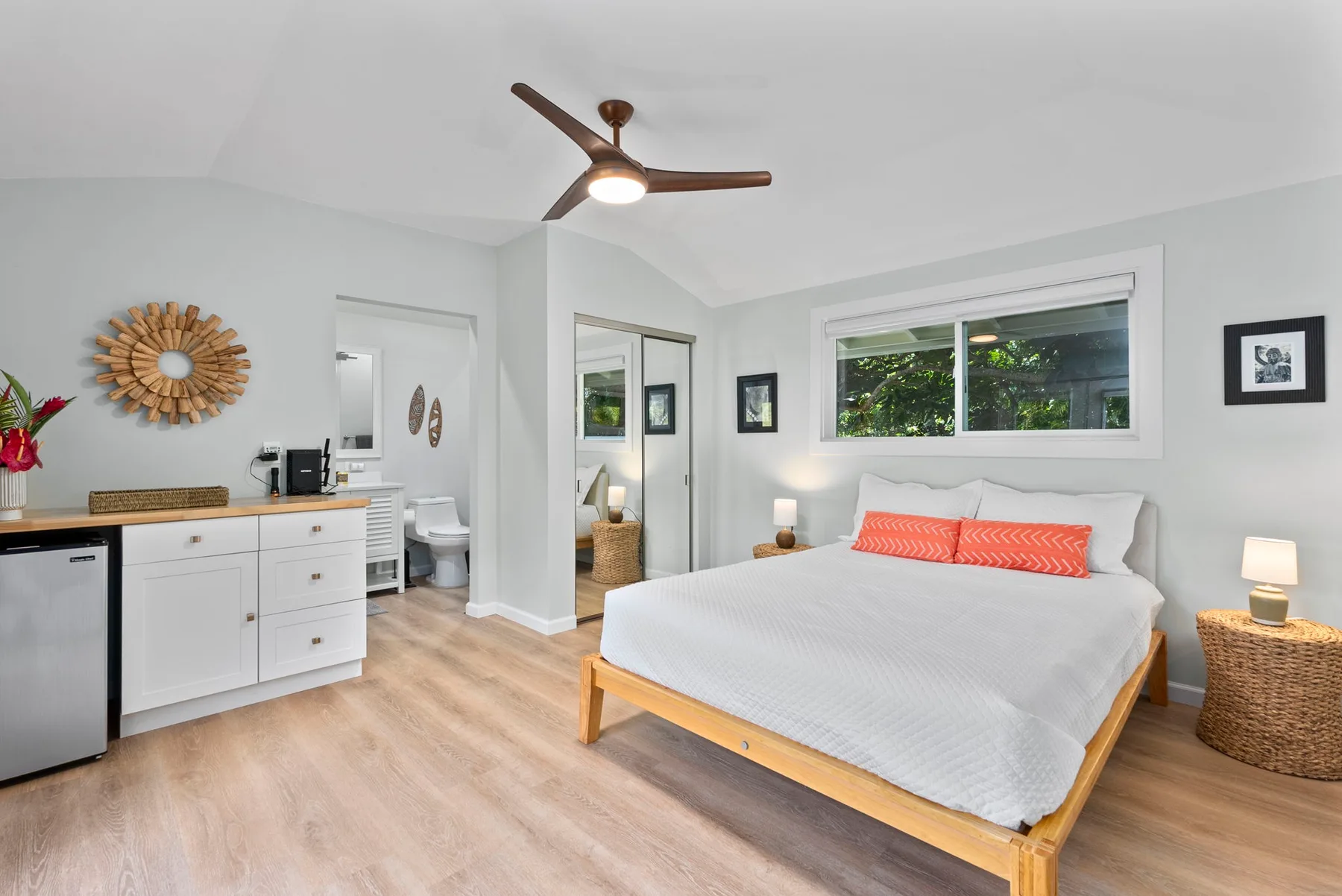 Un dormitorio luminoso con una cama, una ventana amplia y un ventilador de techo.