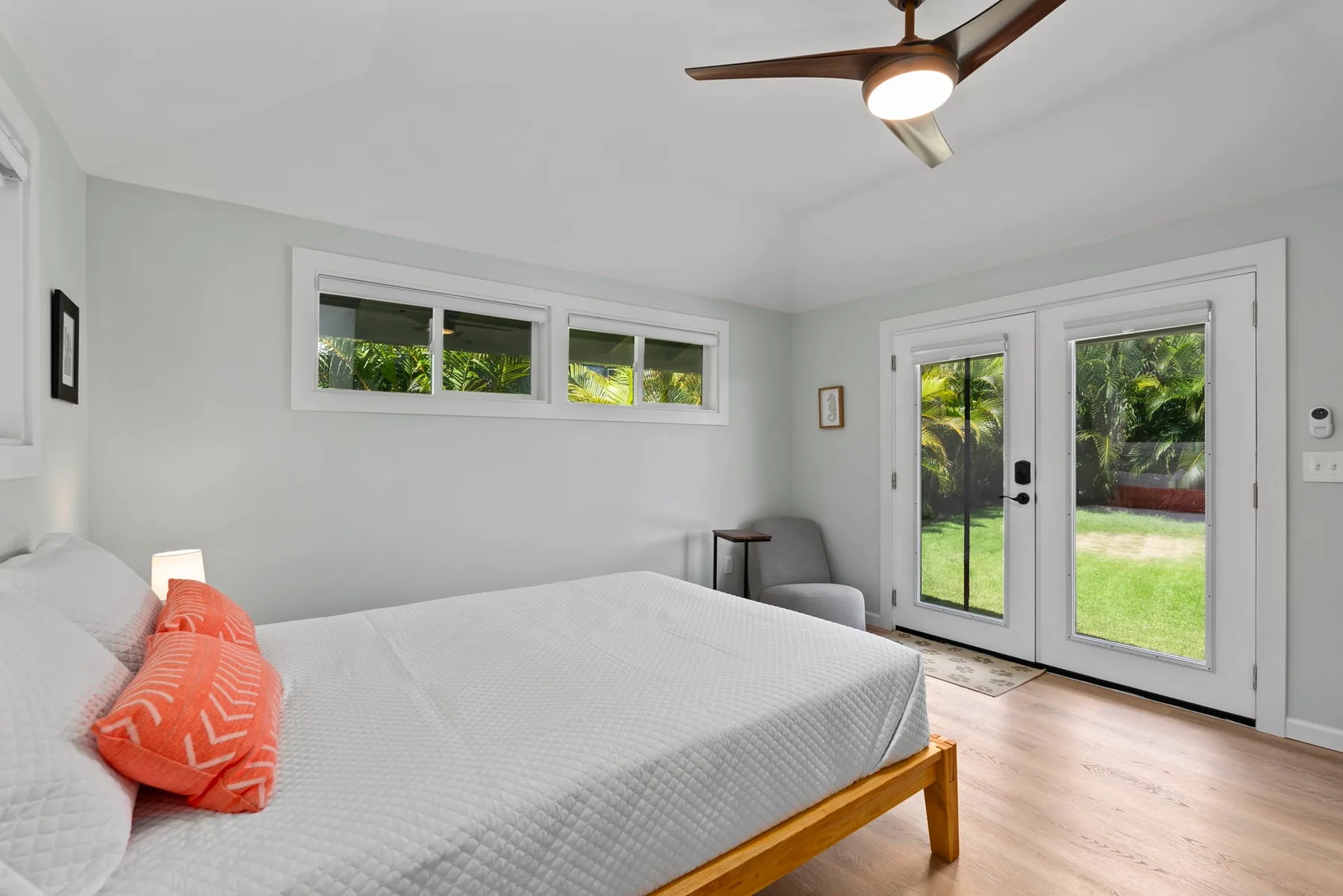 Un dormitorio con una cama junto a puertas de vidrio que dan a un jardín.