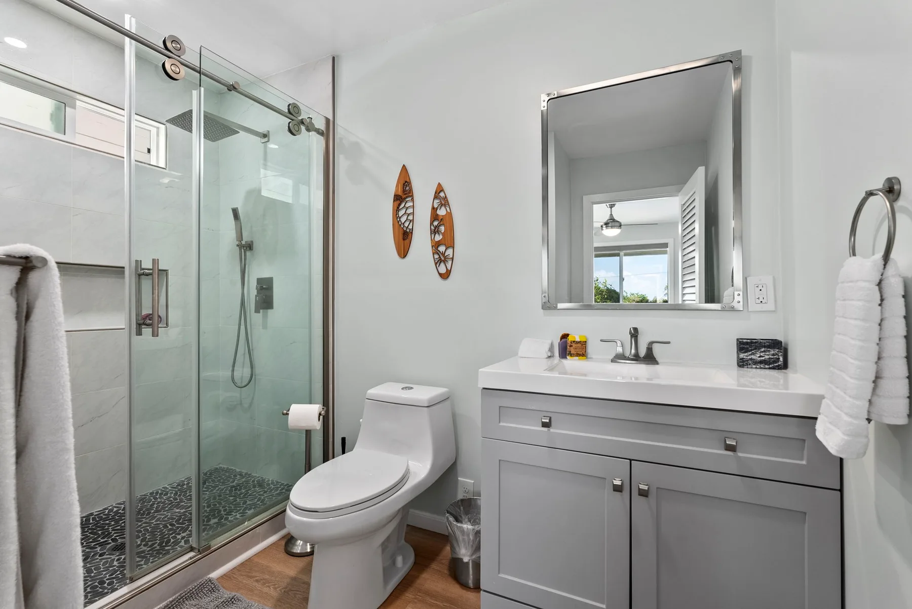 Un baño luminoso con ducha de vidrio, inodoro y lavabo con mueble.