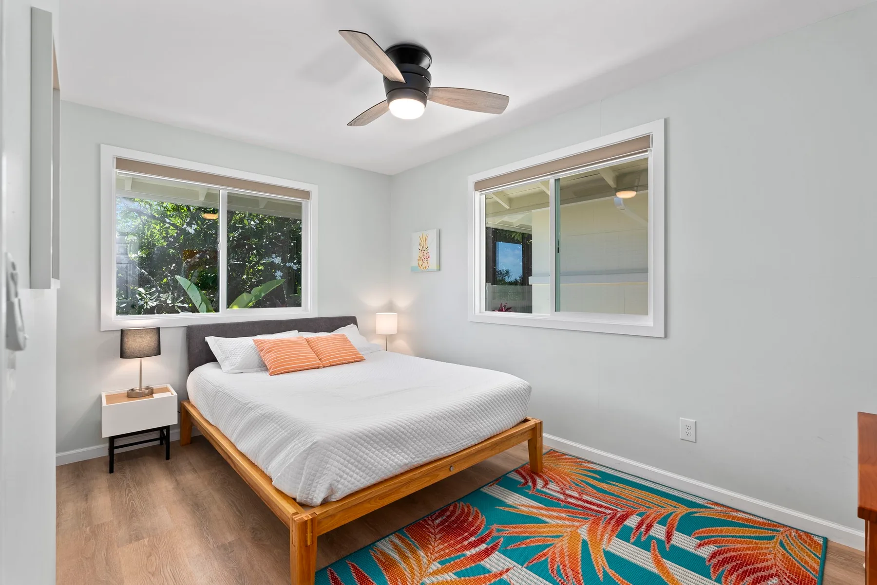 Un dormitorio luminoso con una cama bien tendida y una alfombra colorida.