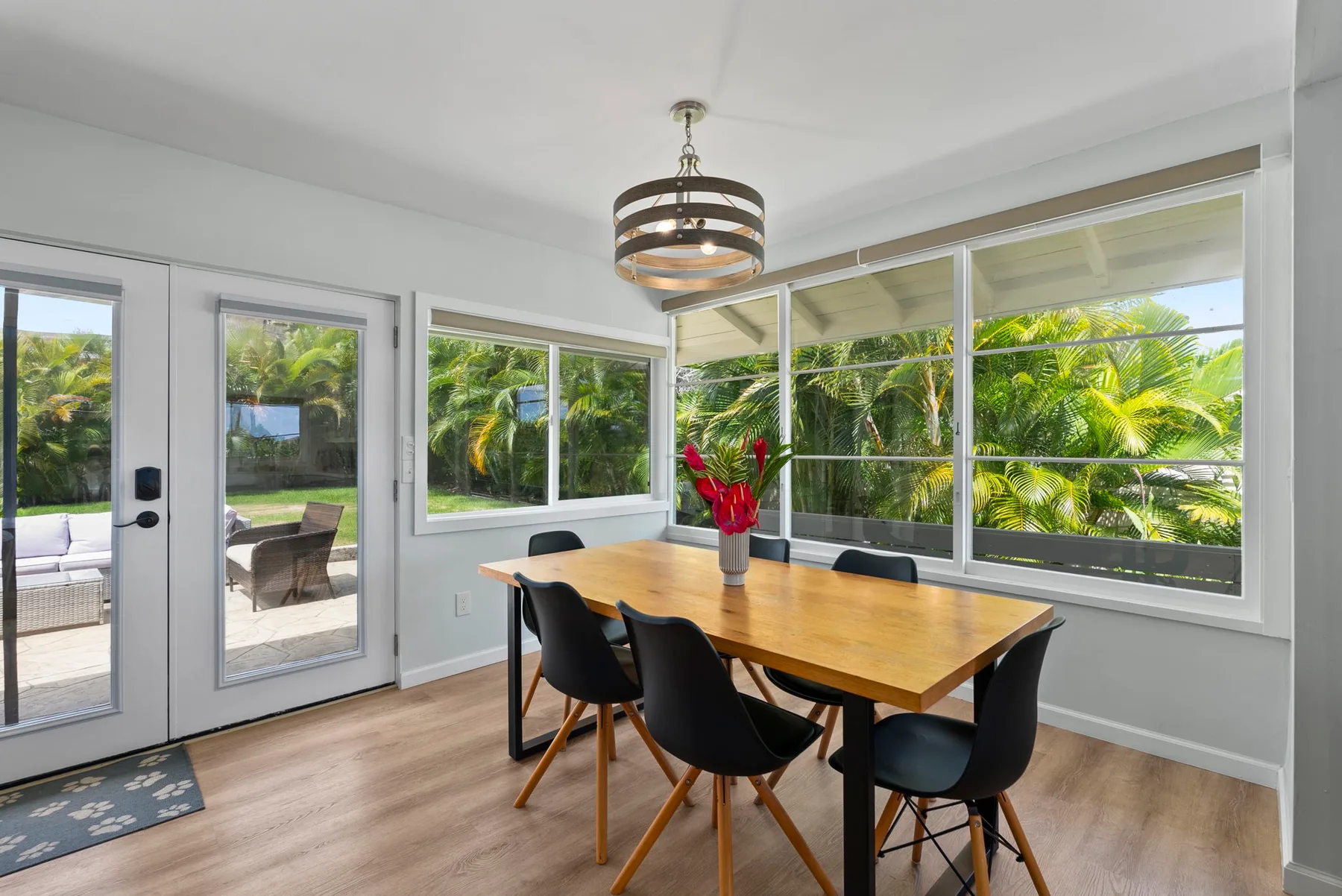 Un comedor luminoso con una mesa de madera junto a grandes ventanas con vistas a la vegetación.