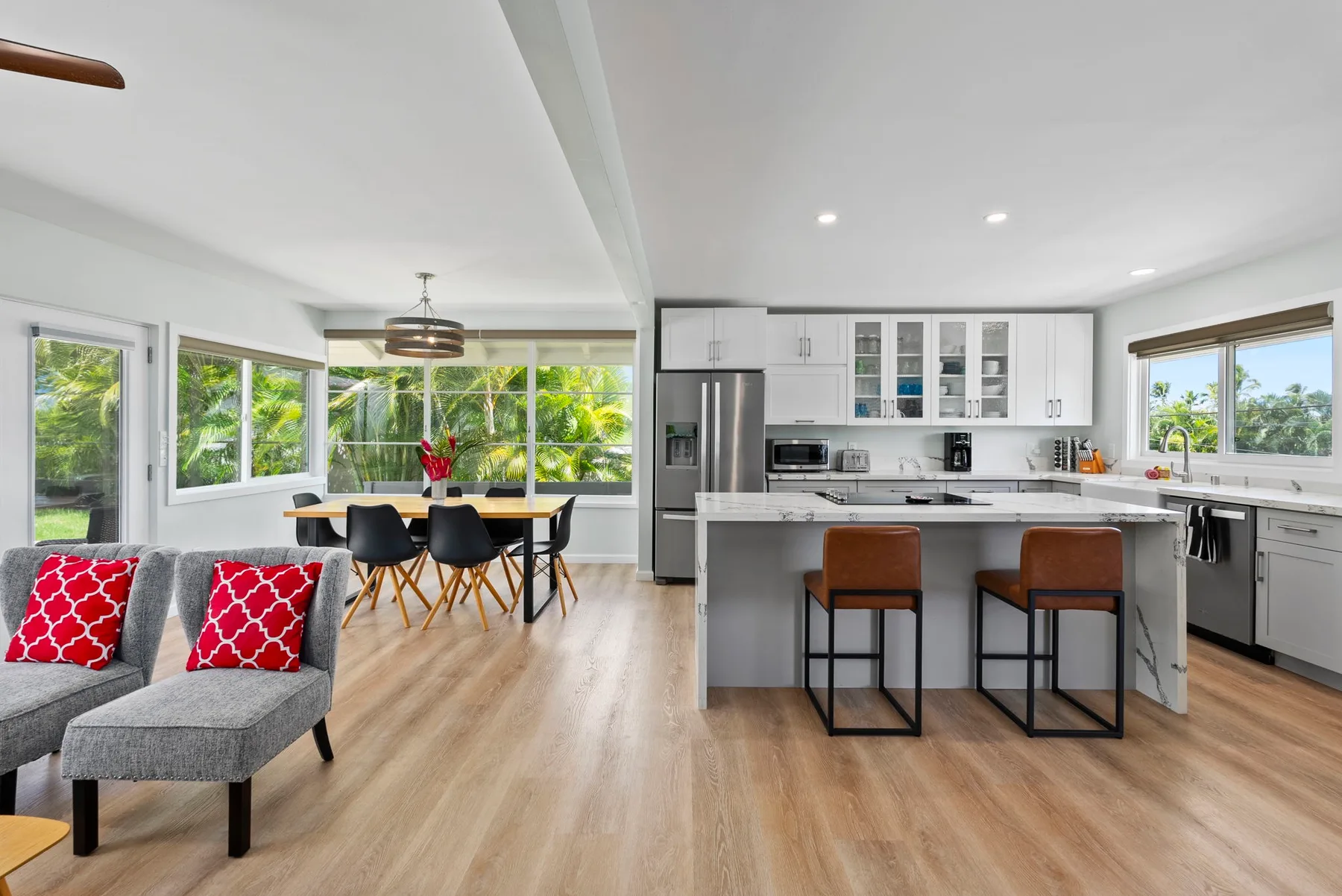 Una luminosa cocina-comedor de planta abierta con una isla central y grandes ventanas.