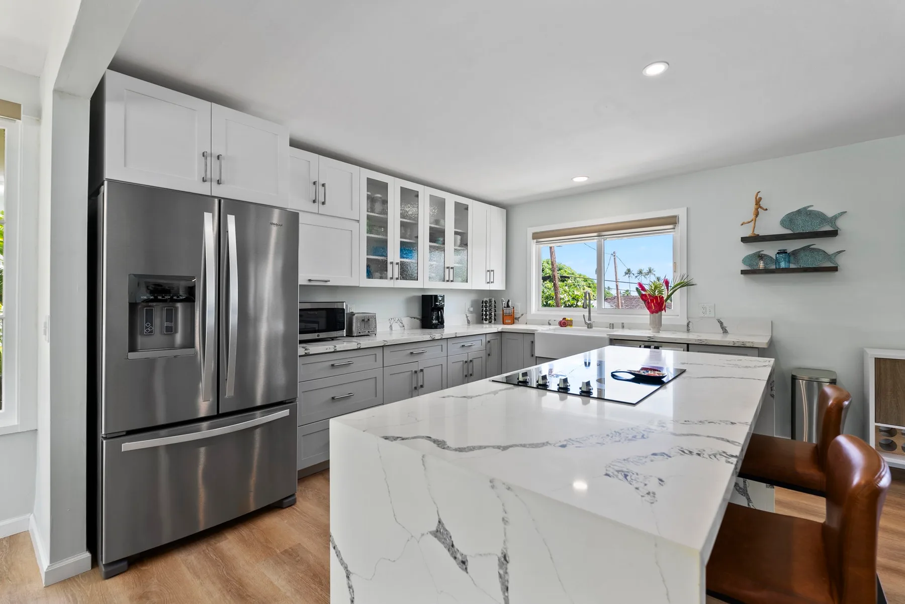 Una cocina luminosa con gabinetes blancos, electrodomésticos de acero inoxidable y una isla grande.