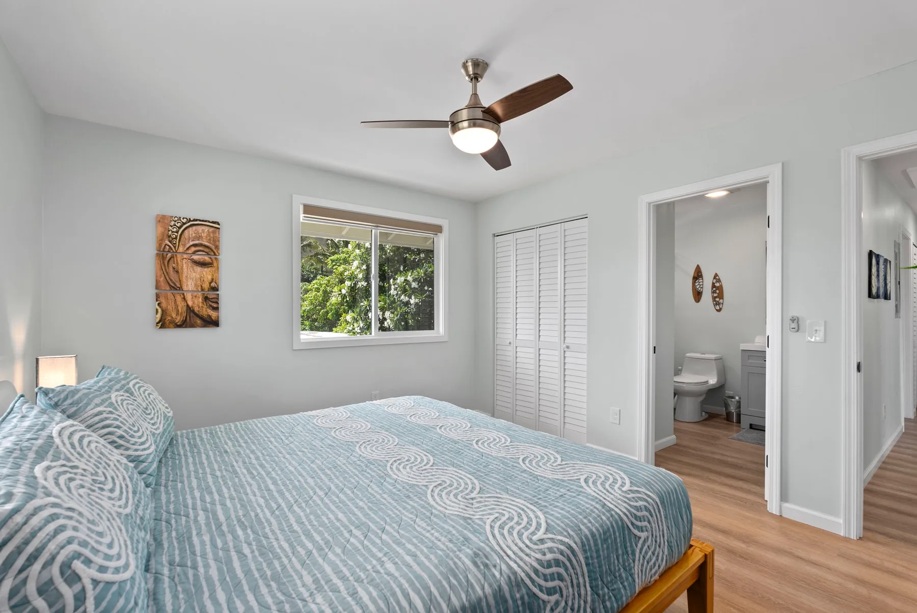 Un dormitorio con una cama, una ventana y una puerta abierta hacia un baño.