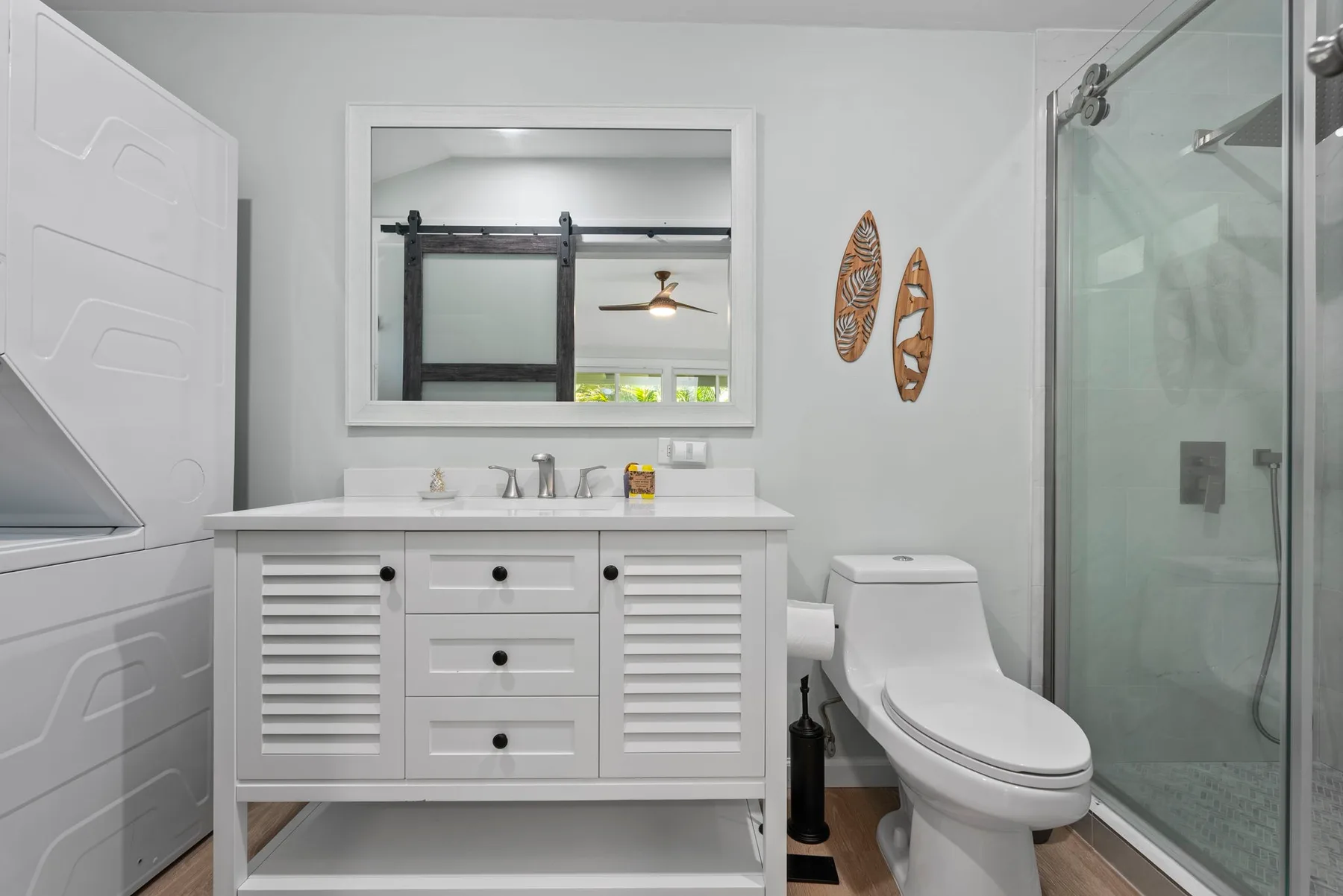 Un baño luminoso con tocador blanco, inodoro y ducha de vidrio.