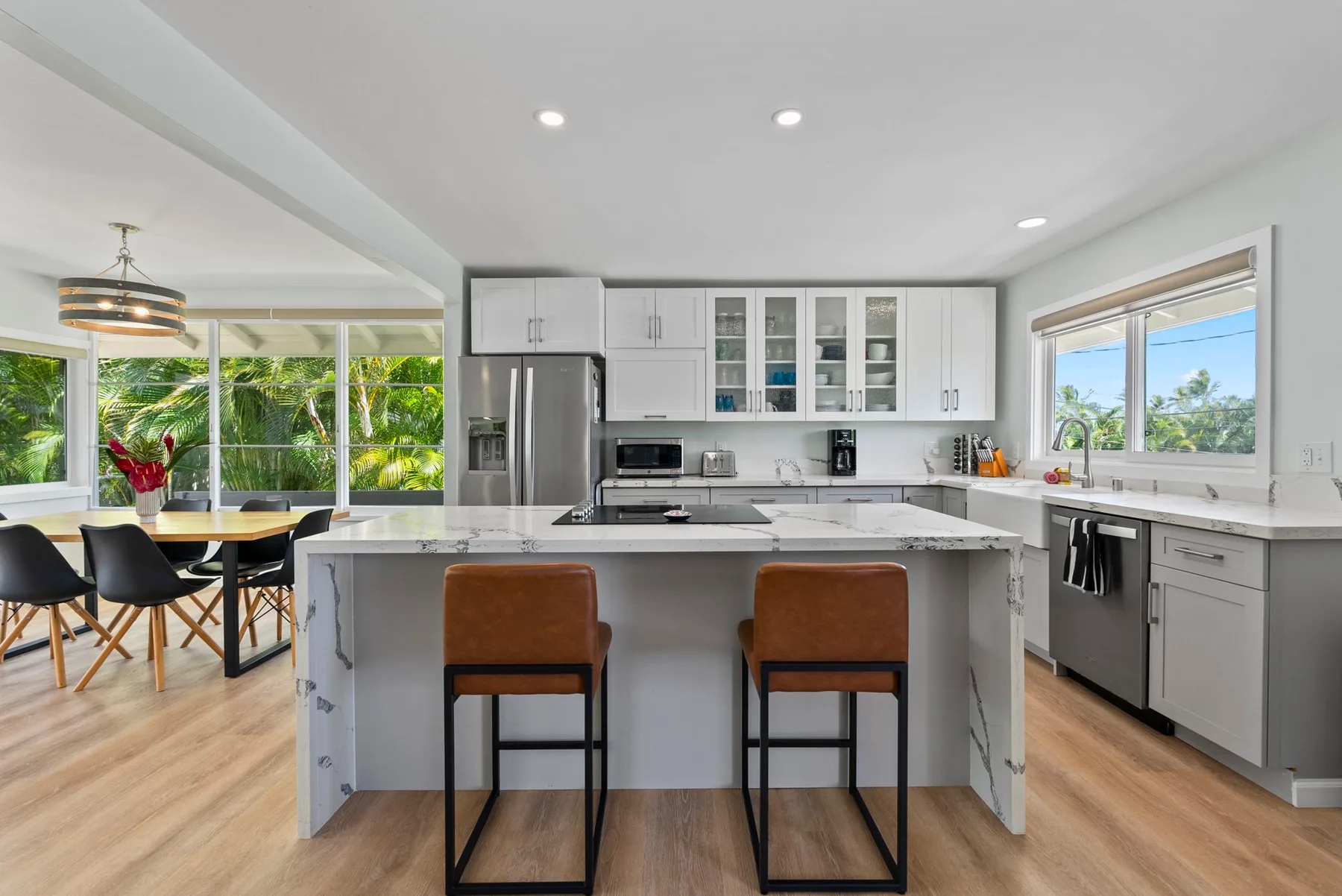 Una cocina luminosa con una isla central y un comedor contiguo.