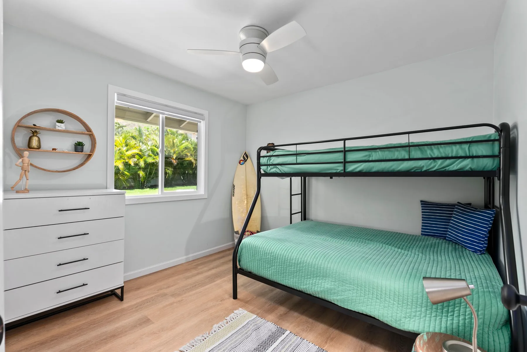 Un dormitorio con una litera, una cómoda y una ventana con vistas a la vegetación.