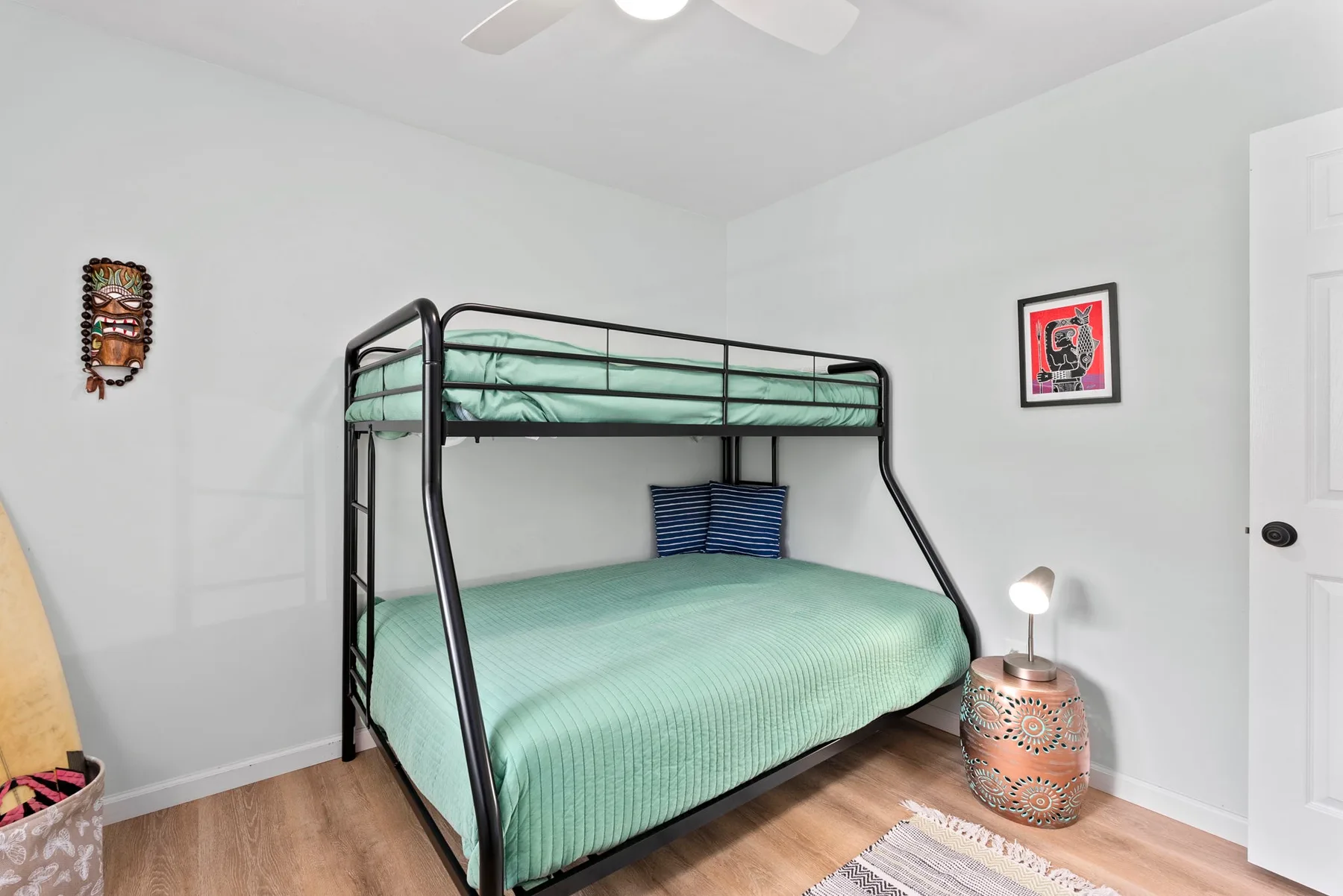 Un dormitorio con una litera, ropa de cama verde menta y arte enmarcado en la pared.