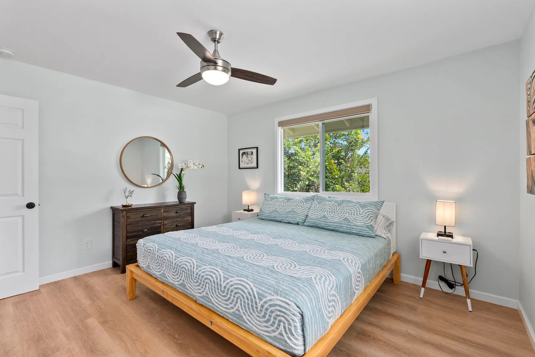 Un dormitorio luminoso con una cama de madera y una ventana con vistas a la vegetación.