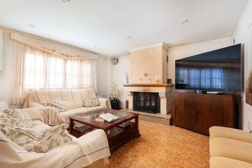 A living room with light-colored seating, a coffee table, and a television.