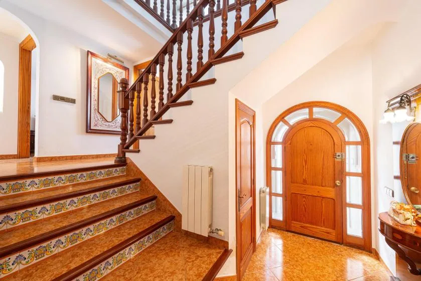 An interior entryway with a wooden staircase and an arched wooden door.