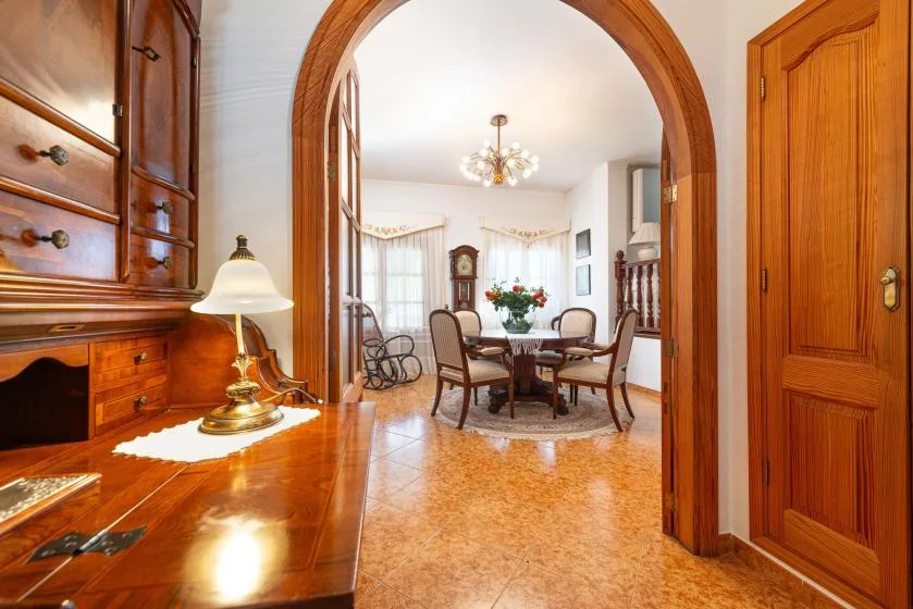 A dining room with a round table and chairs sits beyond a wooden archway.