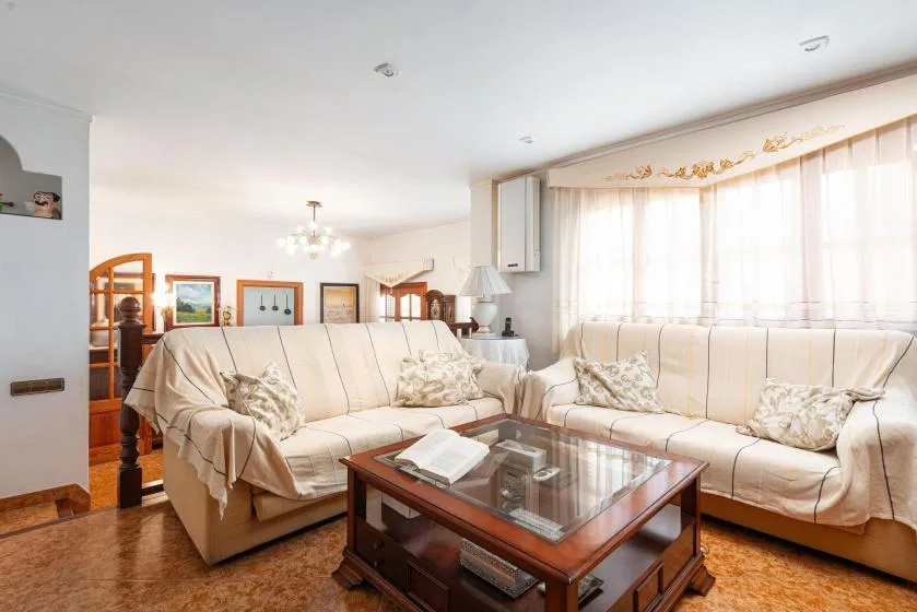A bright living room with cream seating and a glass-topped coffee table.
