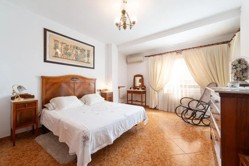 A bedroom with a bed, bedside tables, and curtains around a bright window.