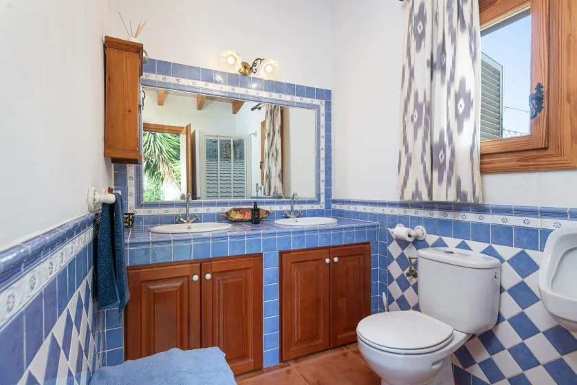 A tiled bathroom with a double-sink vanity, mirror, and toilet.
