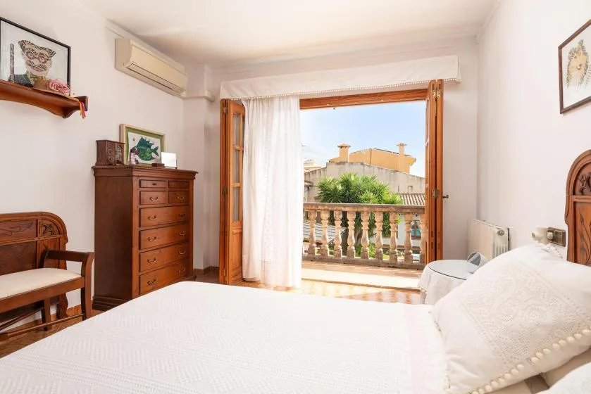 A bedroom with a bed and an open balcony door letting in daylight.