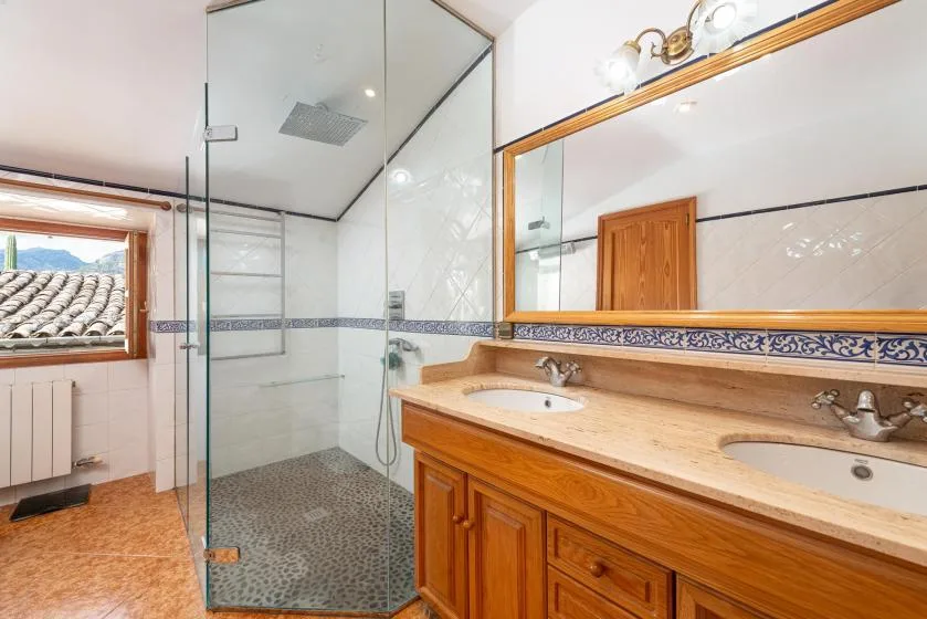 A bathroom with a glass shower and a long wooden vanity.