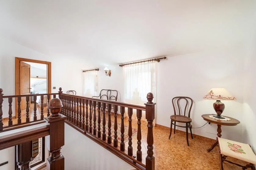 An indoor landing with wooden railing, seating, and a small side table.