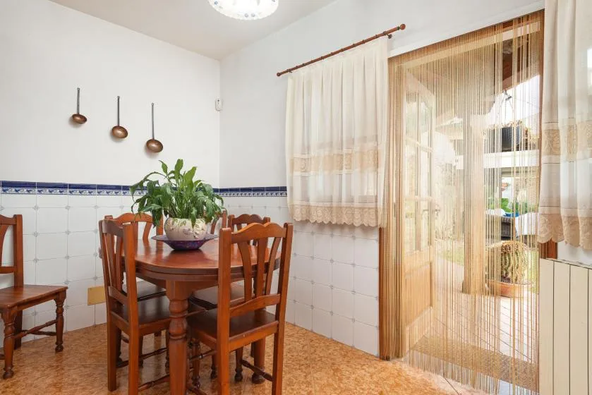 A dining area with a wooden table and chairs beside a curtained glass door.