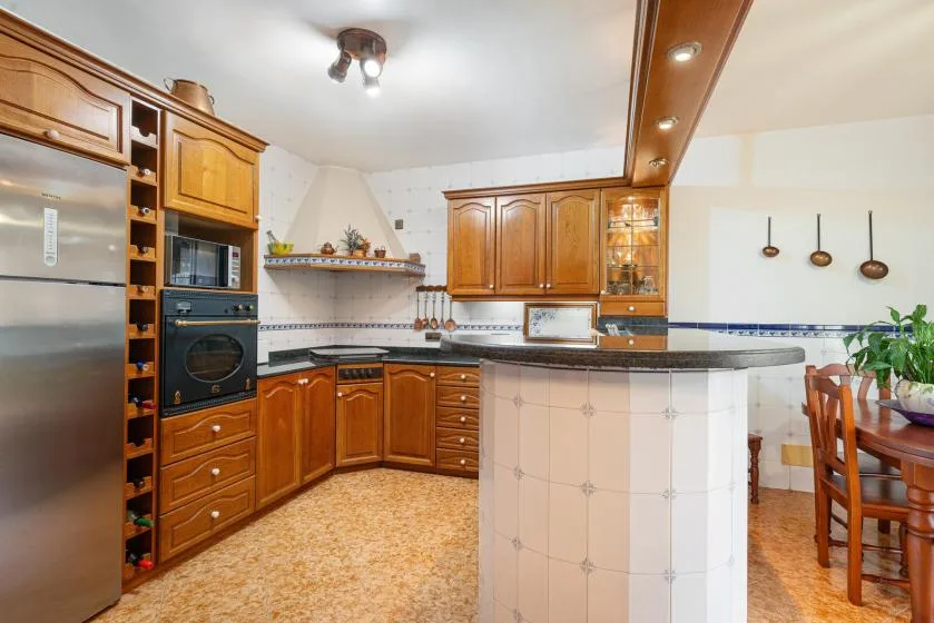 A kitchen with wooden cabinets, built-in appliances, and a curved counter.
