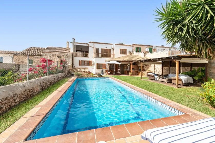 An outdoor swimming pool beside a covered patio and a white building.