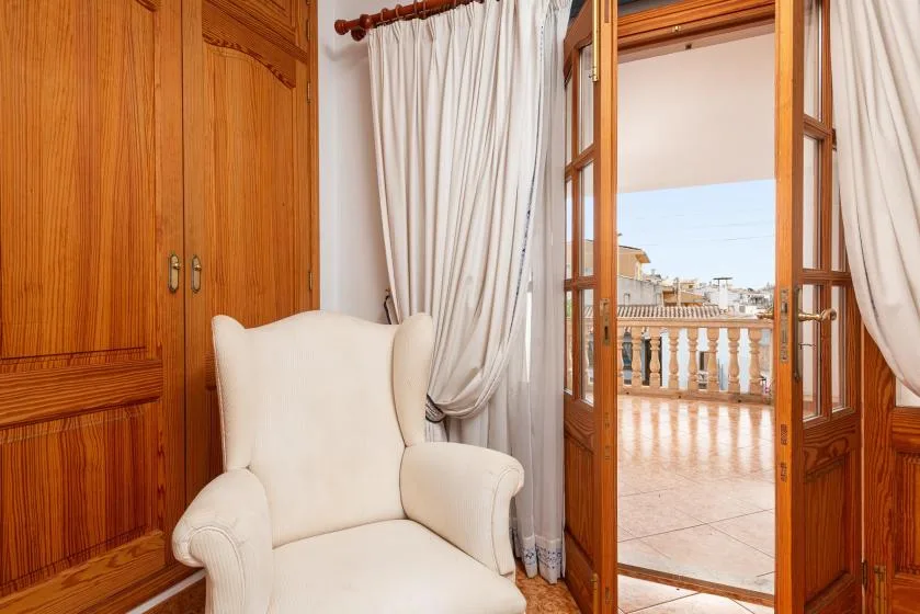 A sitting area with a light-colored armchair beside an open balcony doorway.