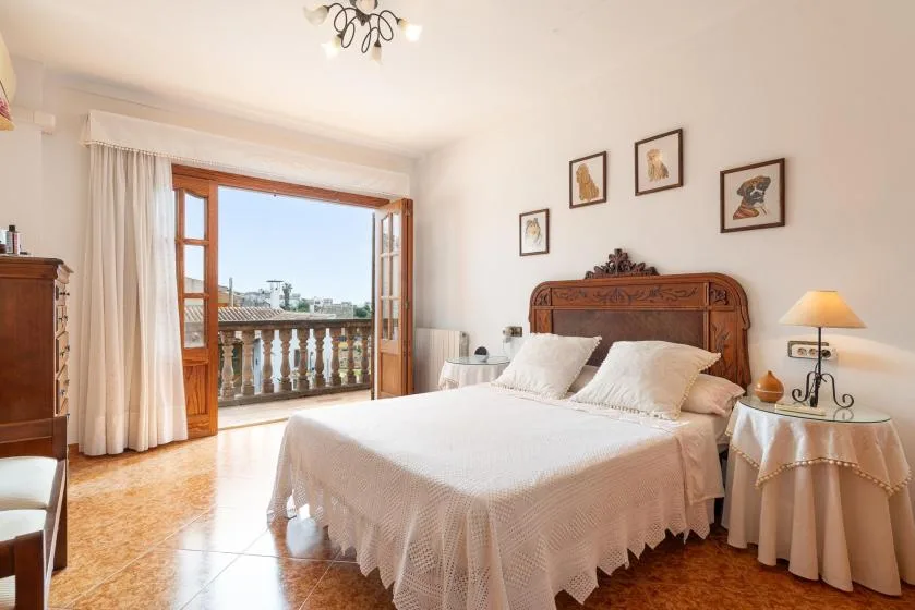 A bright bedroom with a large bed and open balcony doors.