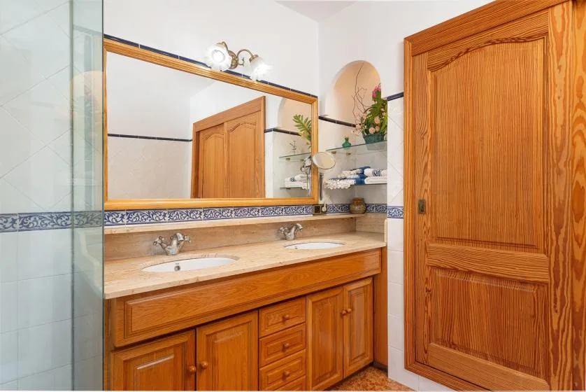 A bathroom vanity with a wide mirror and wooden cabinetry.