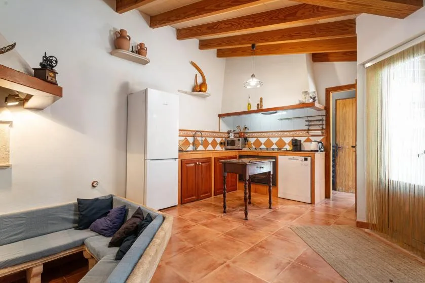 A kitchen and seating area with wooden ceiling beams and tiled flooring.