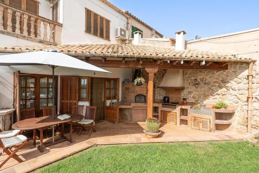 An outdoor patio with dining seating, a fireplace, and a small lawn.