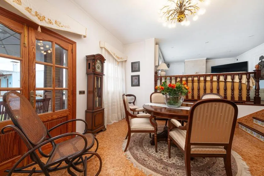 A bright dining area with a wooden table, chairs, and a floral centerpiece.