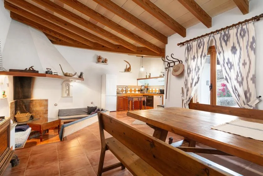 A rustic dining area with a long wooden table beneath exposed ceiling beams.